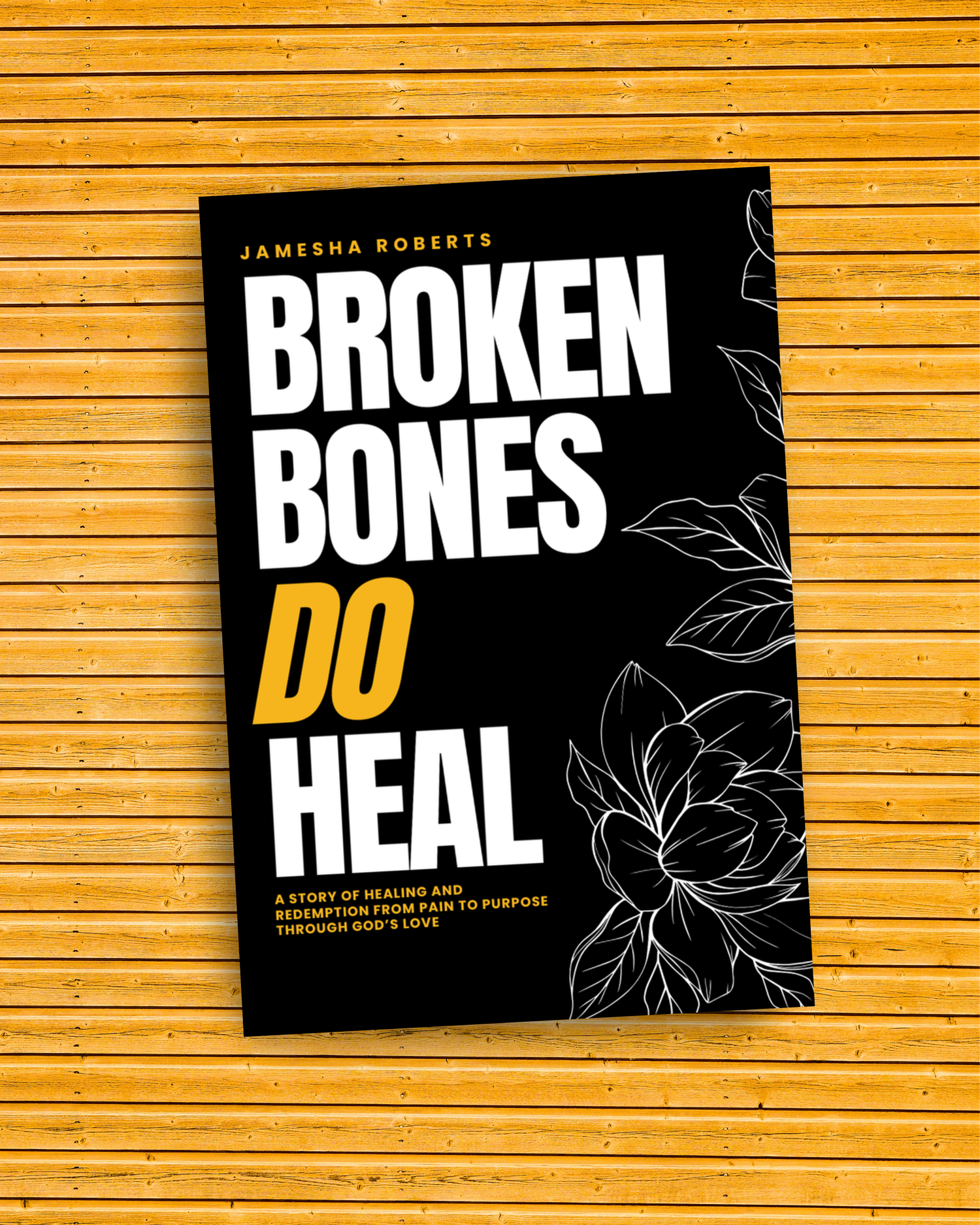 Book cover of 'Broken Bones Do Heal' by Jamesha Roberts on a wooden surface